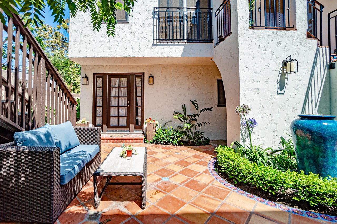 Spanish-style courtyard home in Belmont Heights Long Beach with tiled patio, outdoor seating, and lush landscaping