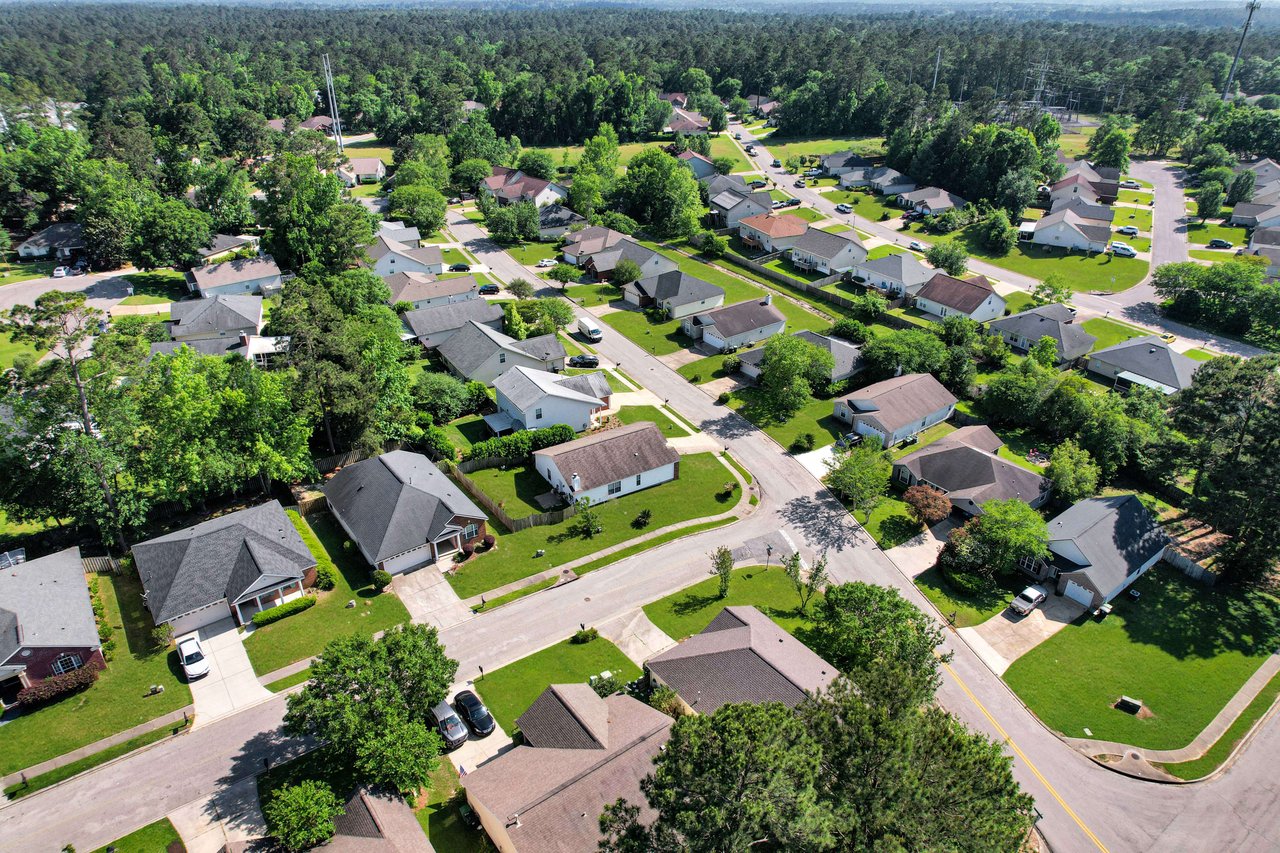 An aerial view of the Killearn Lakes community, showing houses, streets, and surrounding green spaces.