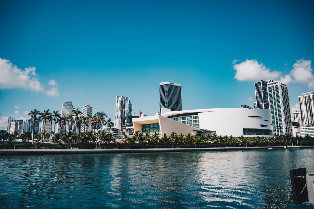 Miami waterfront skyline with the Kaseya Center, palm trees, and high-rise buildings.