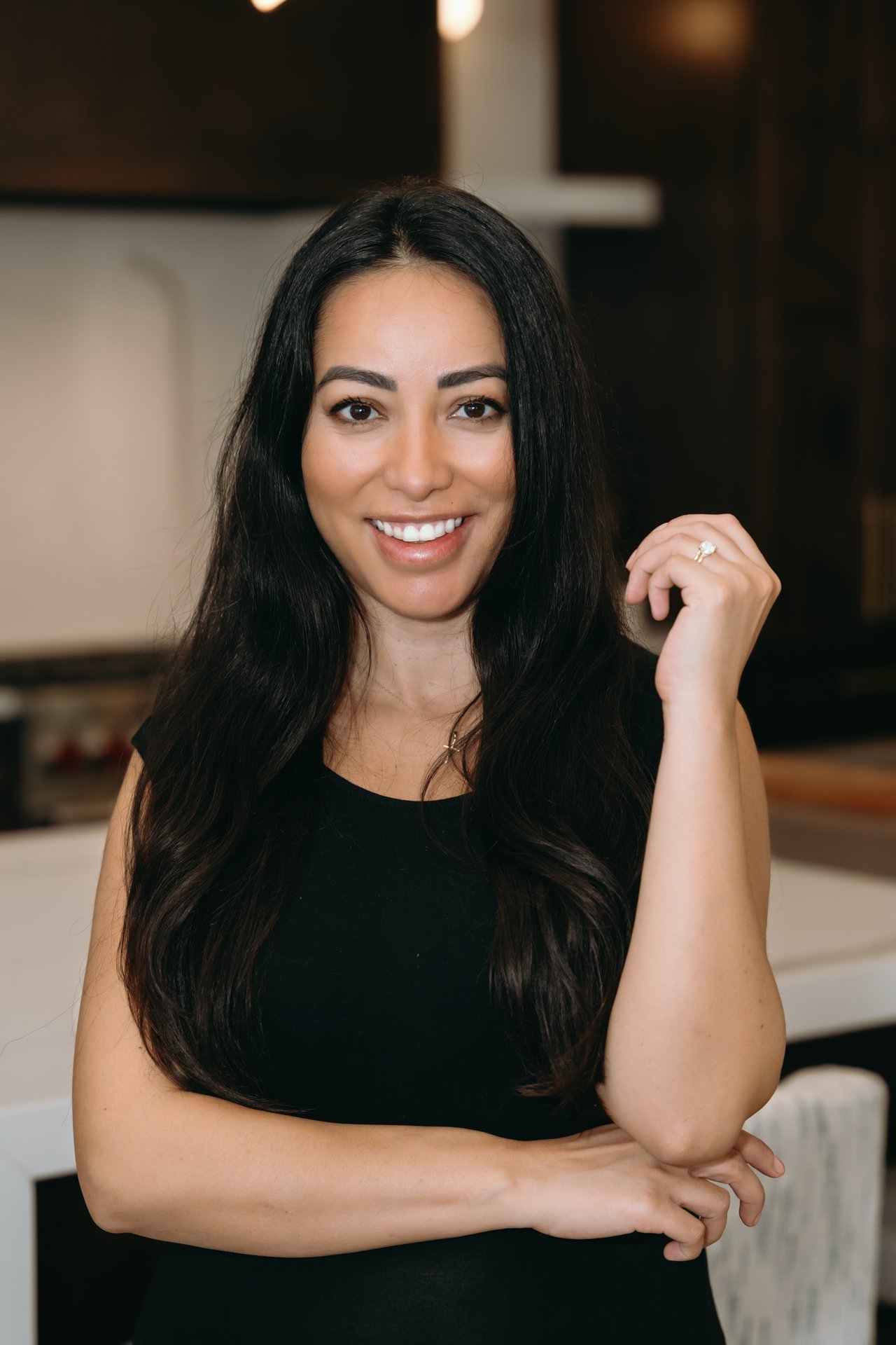 Angee Olson smiling with long dark hair in a black sleeveless top.