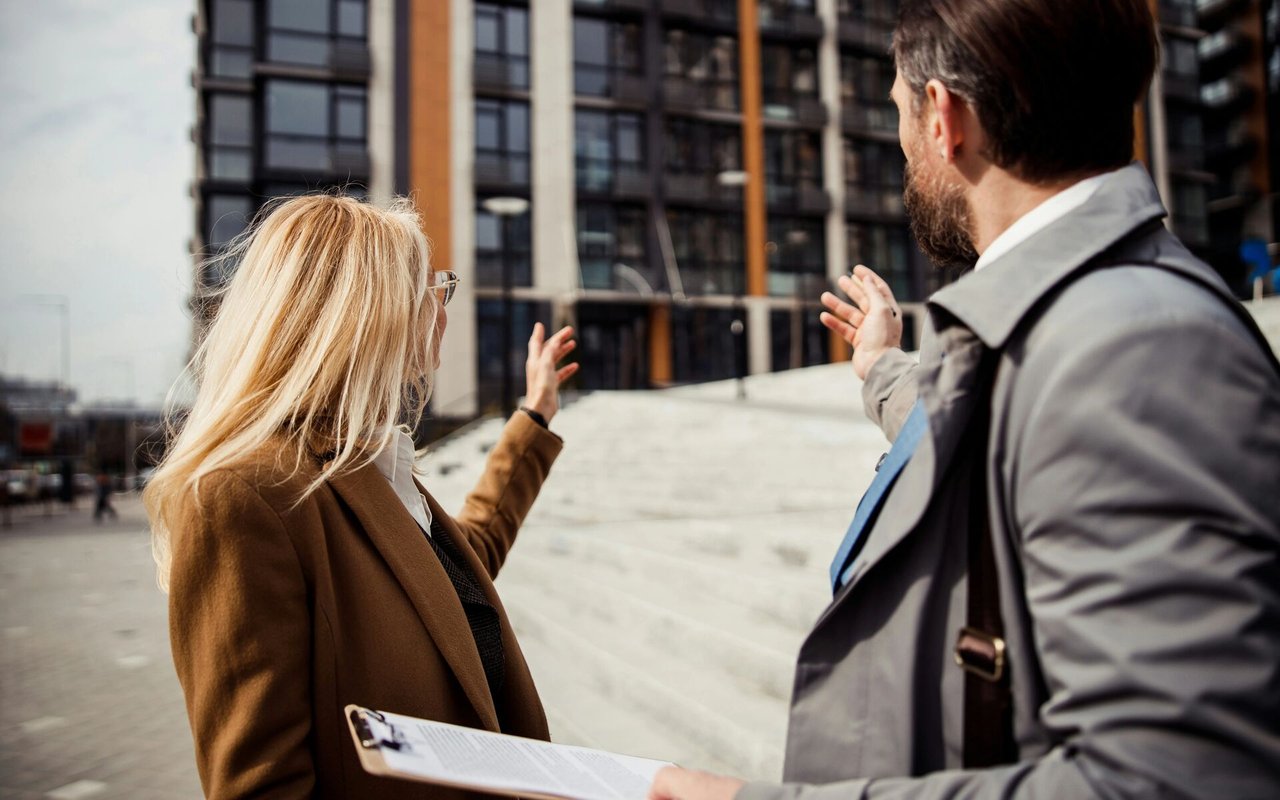 A woman and man discuss a modern building during a real estate viewing.