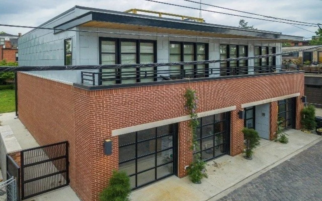 Modern mixed-use building with a brick ground floor and a long upper-level terrace.