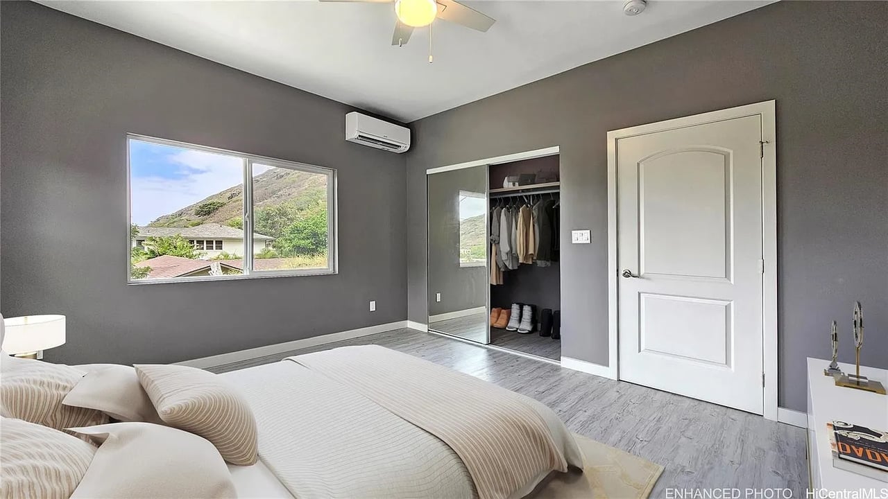 Bedroom with gray walls, a mirrored closet, and a window overlooking a mountain slope.