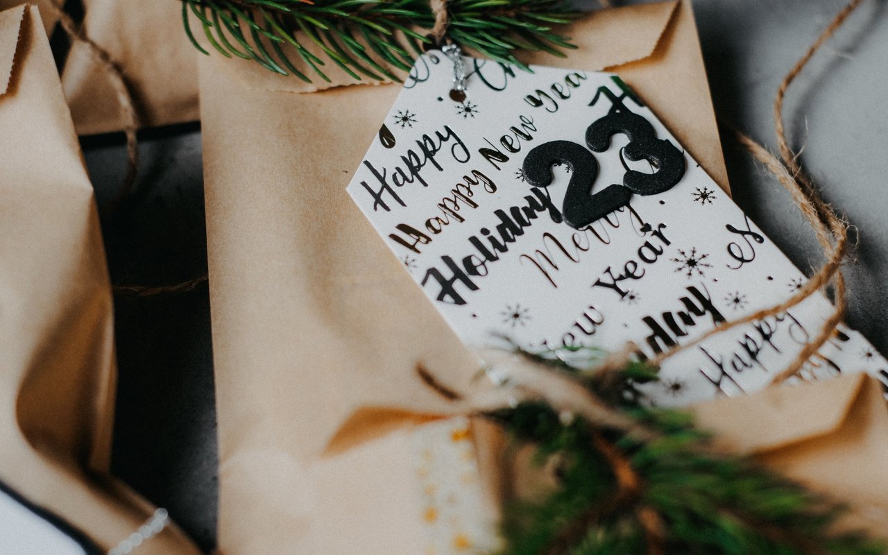 Wrapped holiday gifts with twine, evergreen sprigs, and a tag marked “2023.”