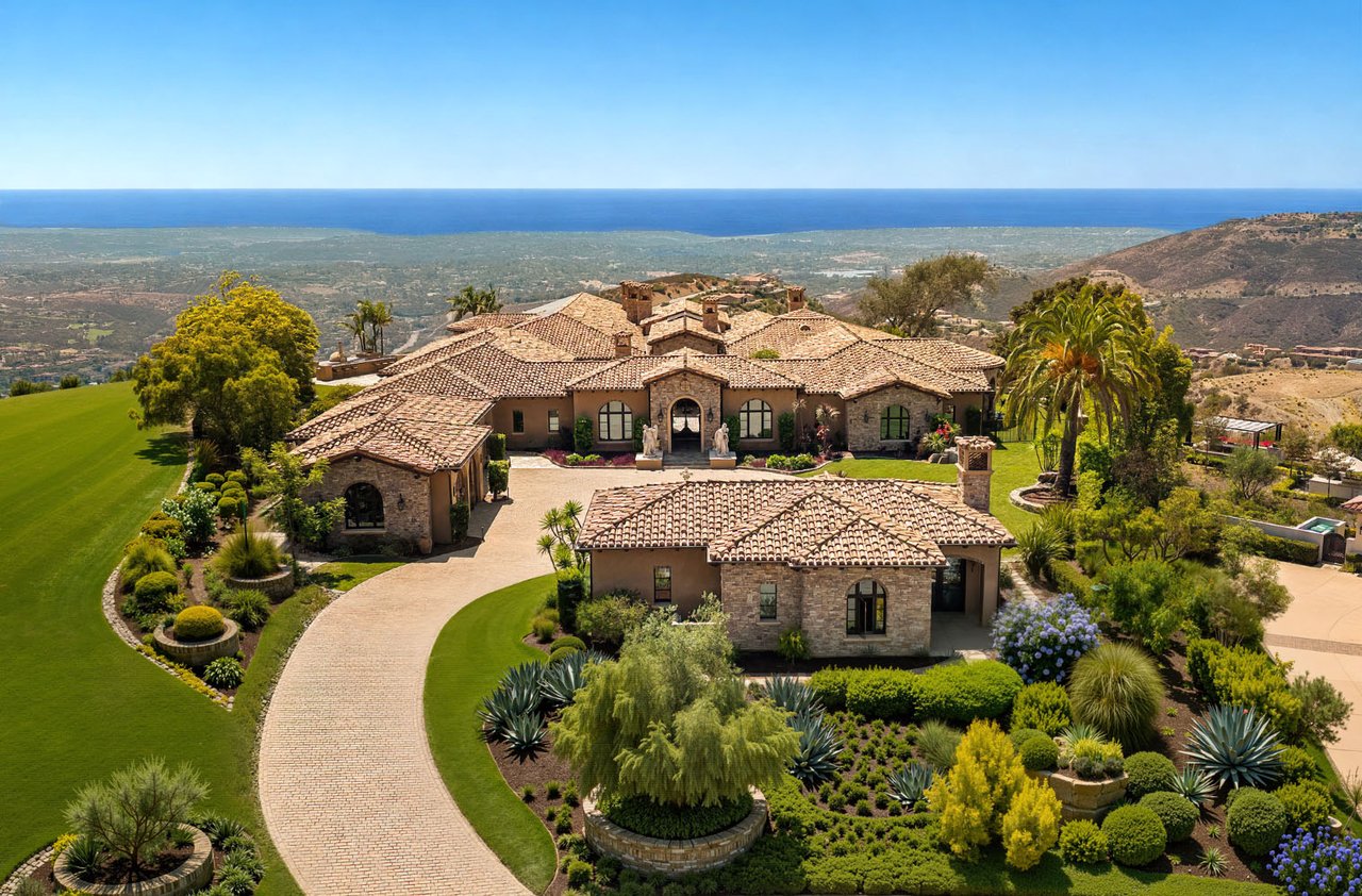 Spanish-style estate with terracotta roofs, landscaped grounds, and a distant ocean view.