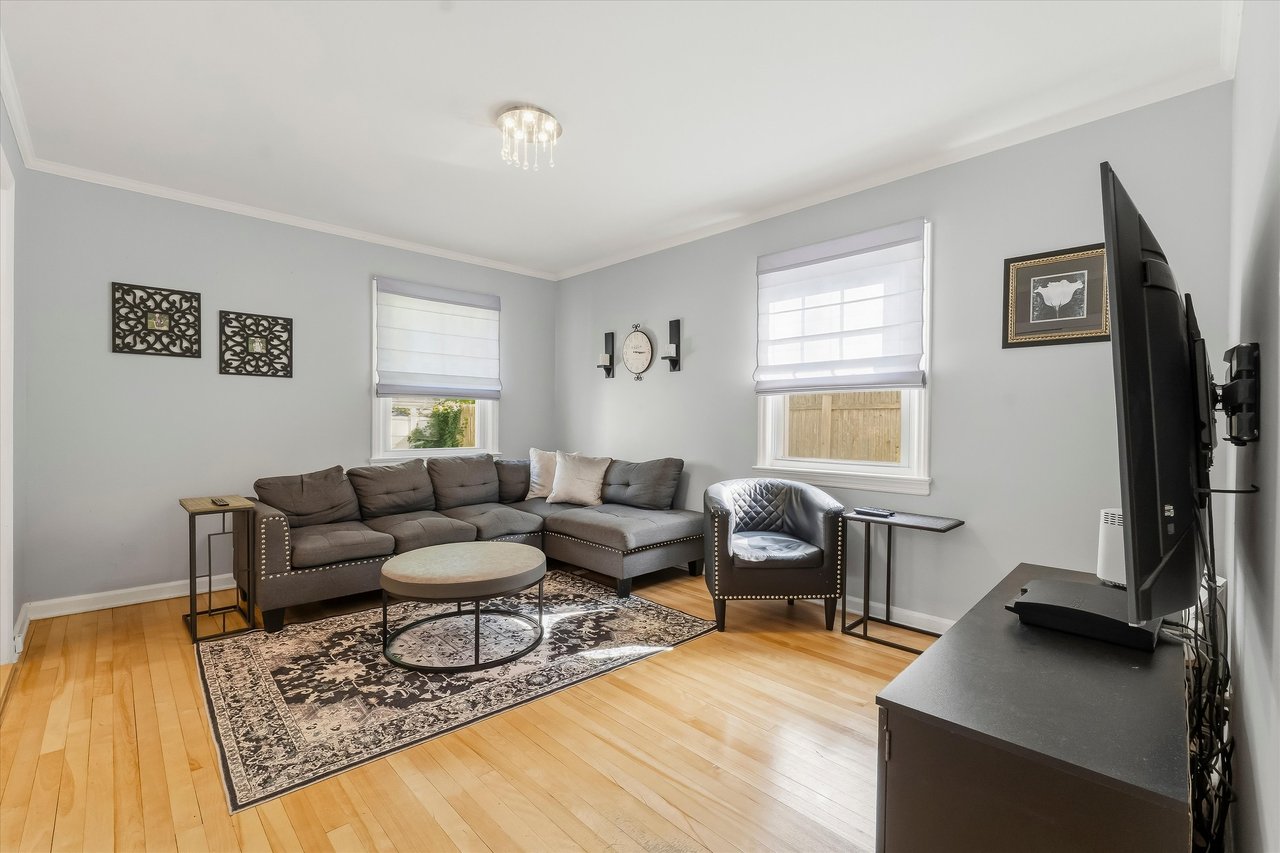 Living room with a gray sectional, patterned rug, round coffee table, and hardwood floors.