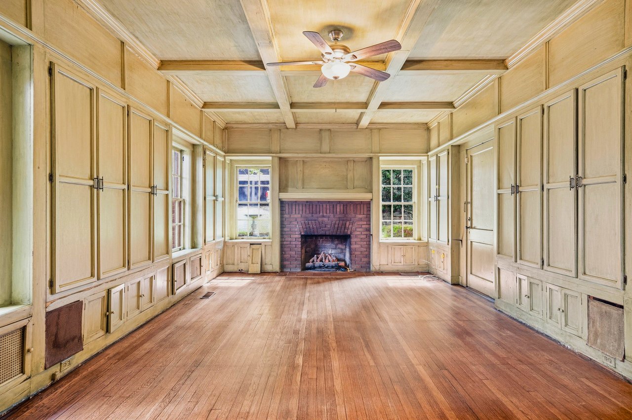 Empty paneled room with built-in cabinets, a brick fireplace, and a coffered ceiling.