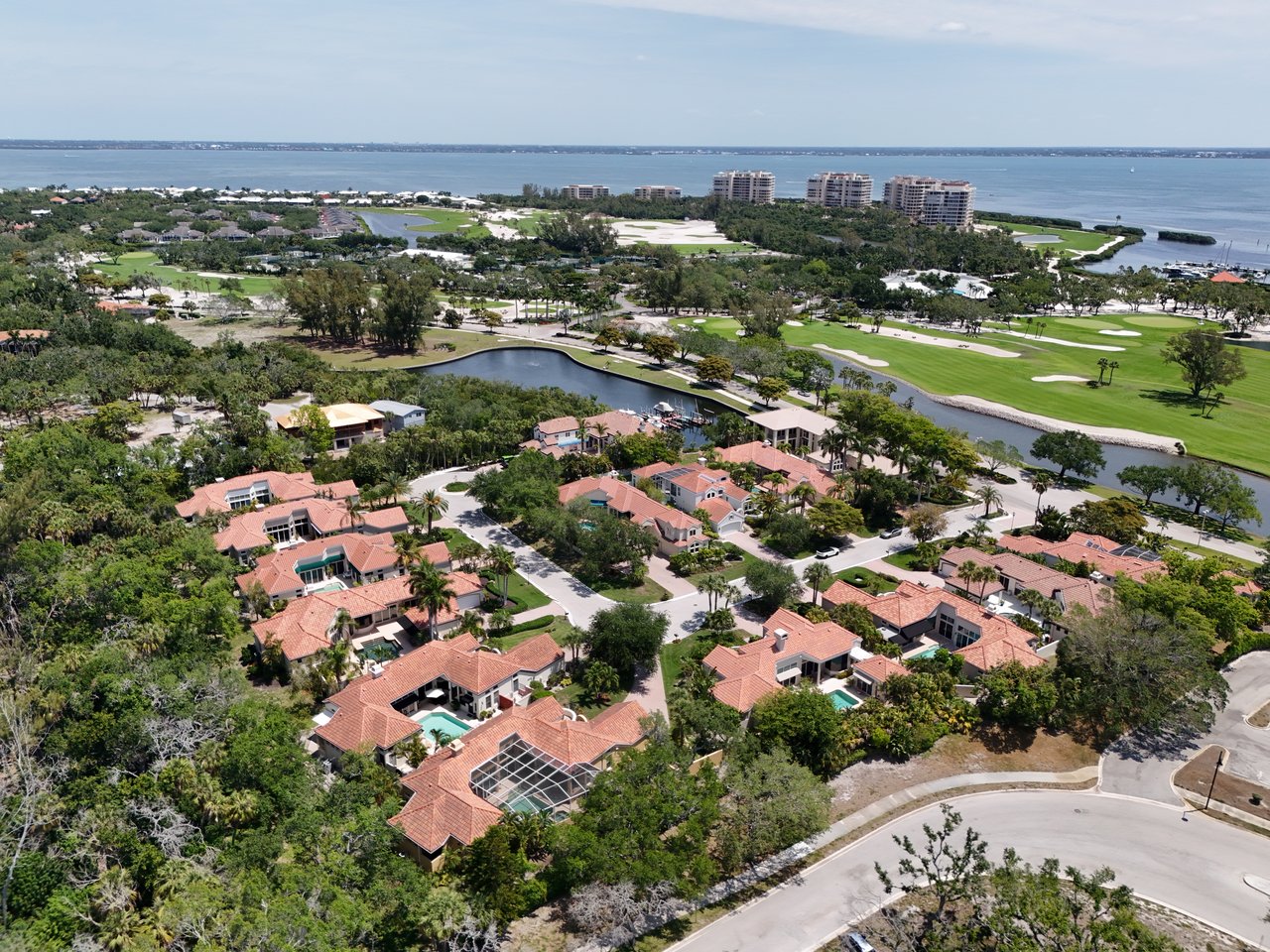 Aerial view of coastal homes beside a golf course, waterways and the sea.
