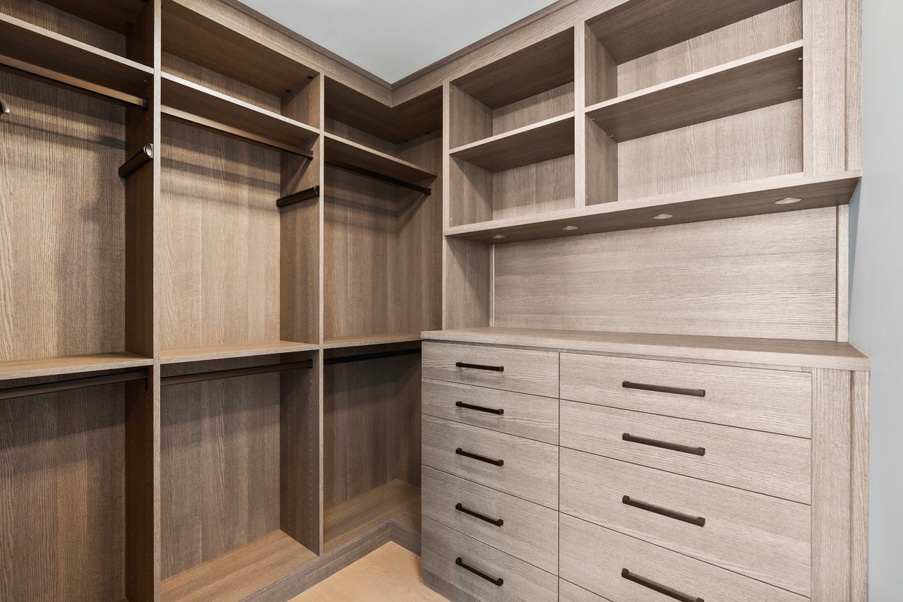 Walk-in closet with light wood shelving and built-in drawers.