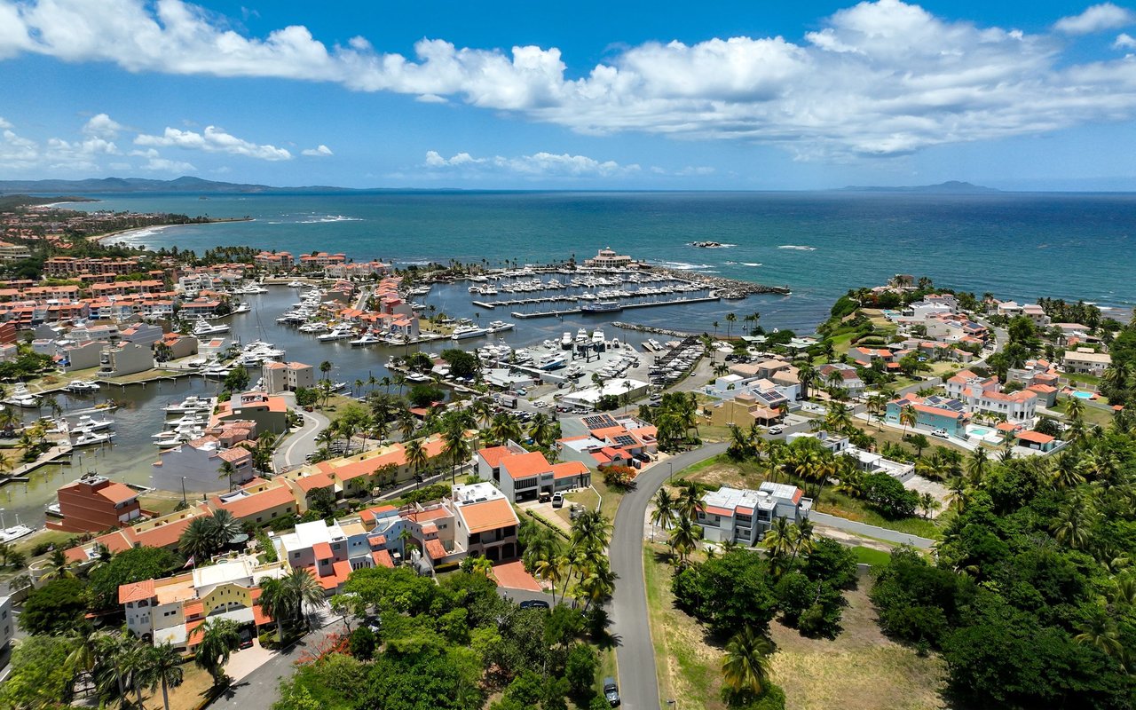 Coastal marina with boats and waterfront homes beside a blue ocean.