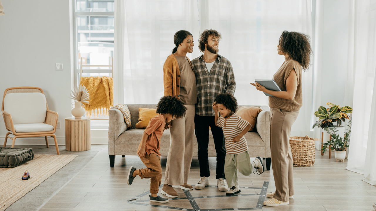 A realtor chats with a smiling family during a home tour in a bright, modern living room—highlighting the warmth and charm found in many homes for sale in Gainesville FL. Gainesville FL realtor, Anna Olcese.