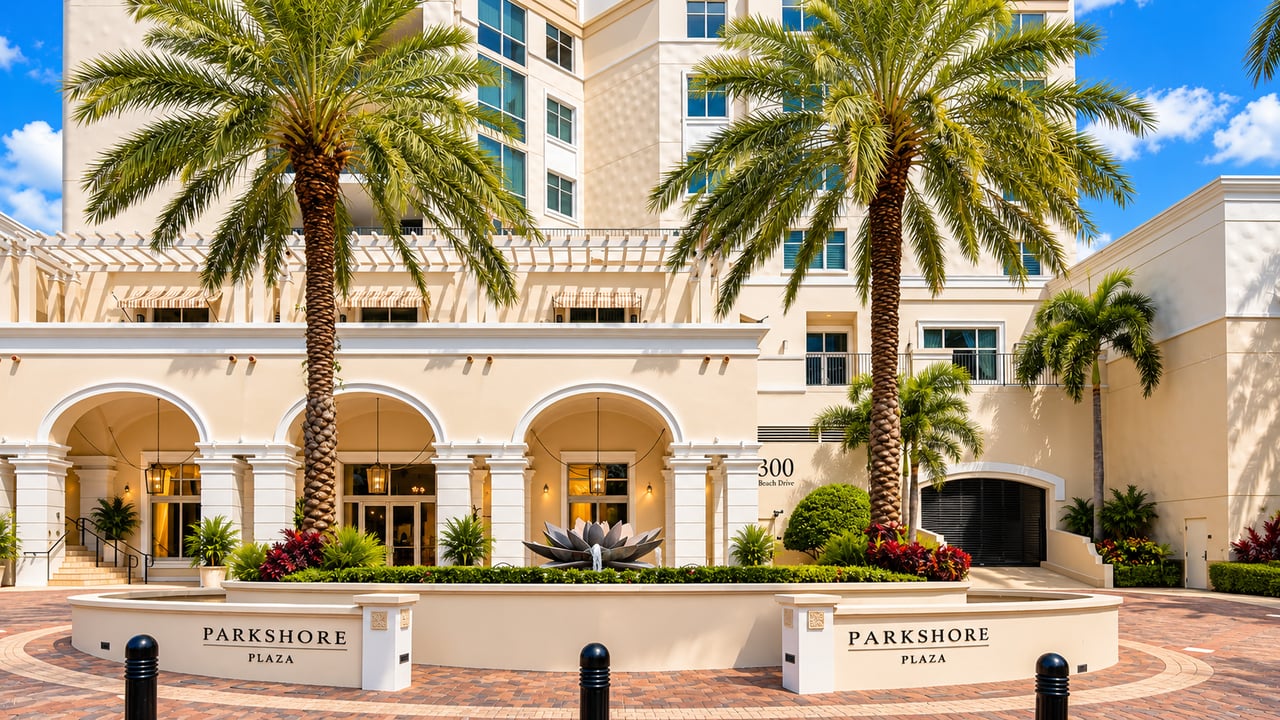 Parkshore Plaza condominium entrance with palm trees, arched entryways, and a landscaped courtyard.