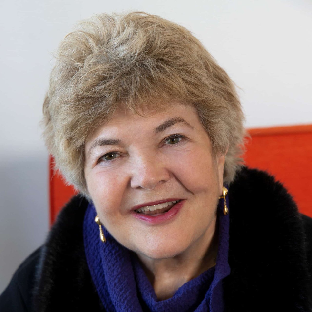 Carren Shagley, founder and associate broker at Legacy Real Estate, formerly part of the Shagley Team. She has shoulder-length brown hair, is wearing a blue top, and is smiling at the camera. The background features a light-colored wall with soft lighting.