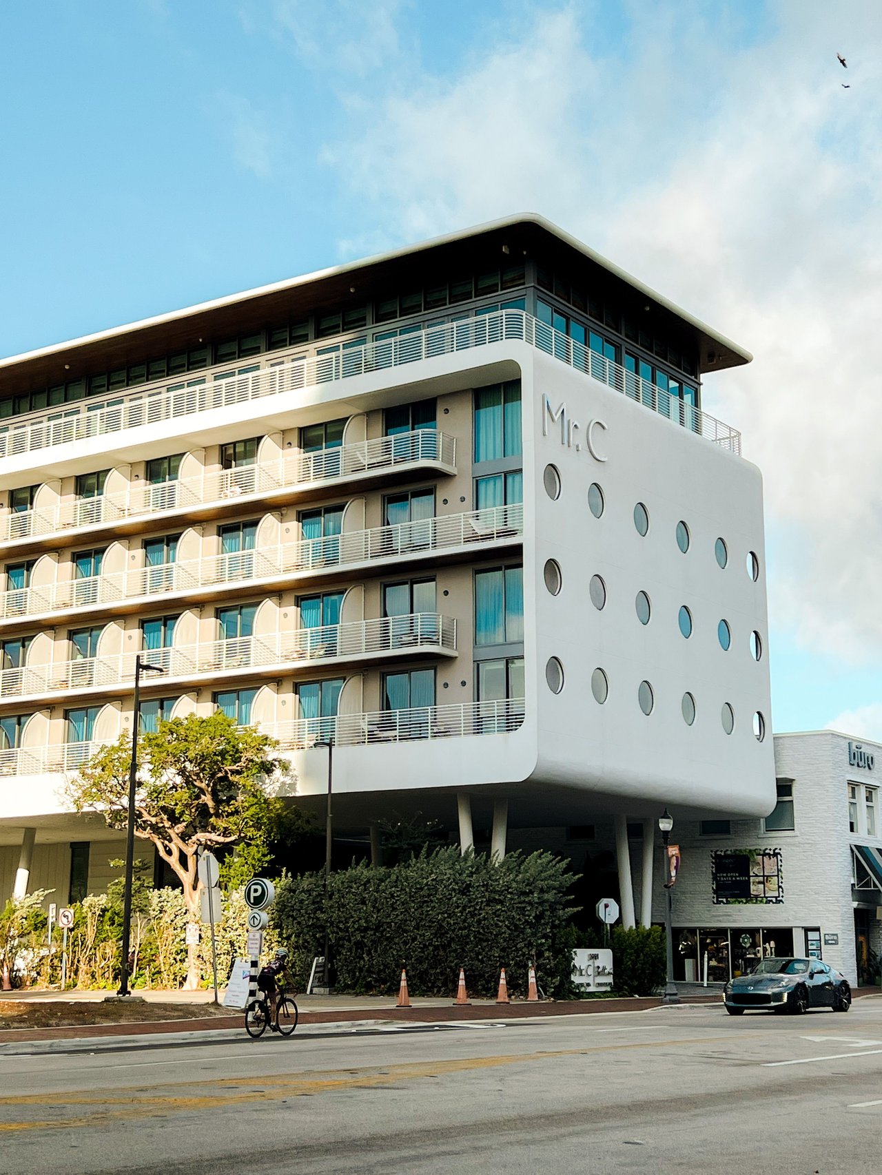 Modern white Mr. C building with stacked balconies and rows of circular windows.