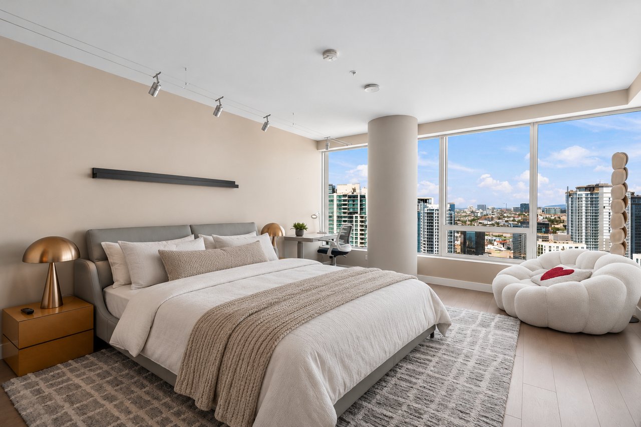 Staged bedroom with a large bed and floor-to-ceiling windows overlooking the downtown skyline.