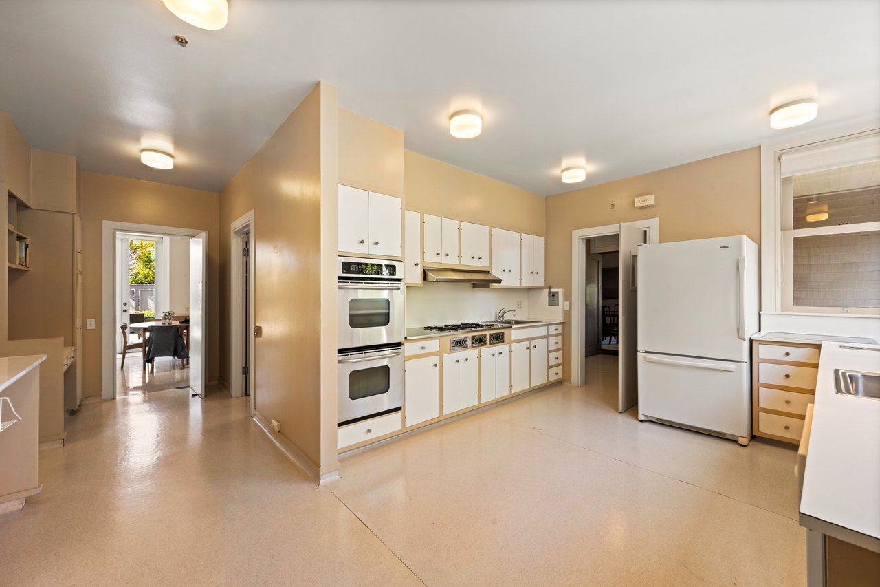 Kitchen with white cabinets, double ovens, gas cooktop, and a large refrigerator.