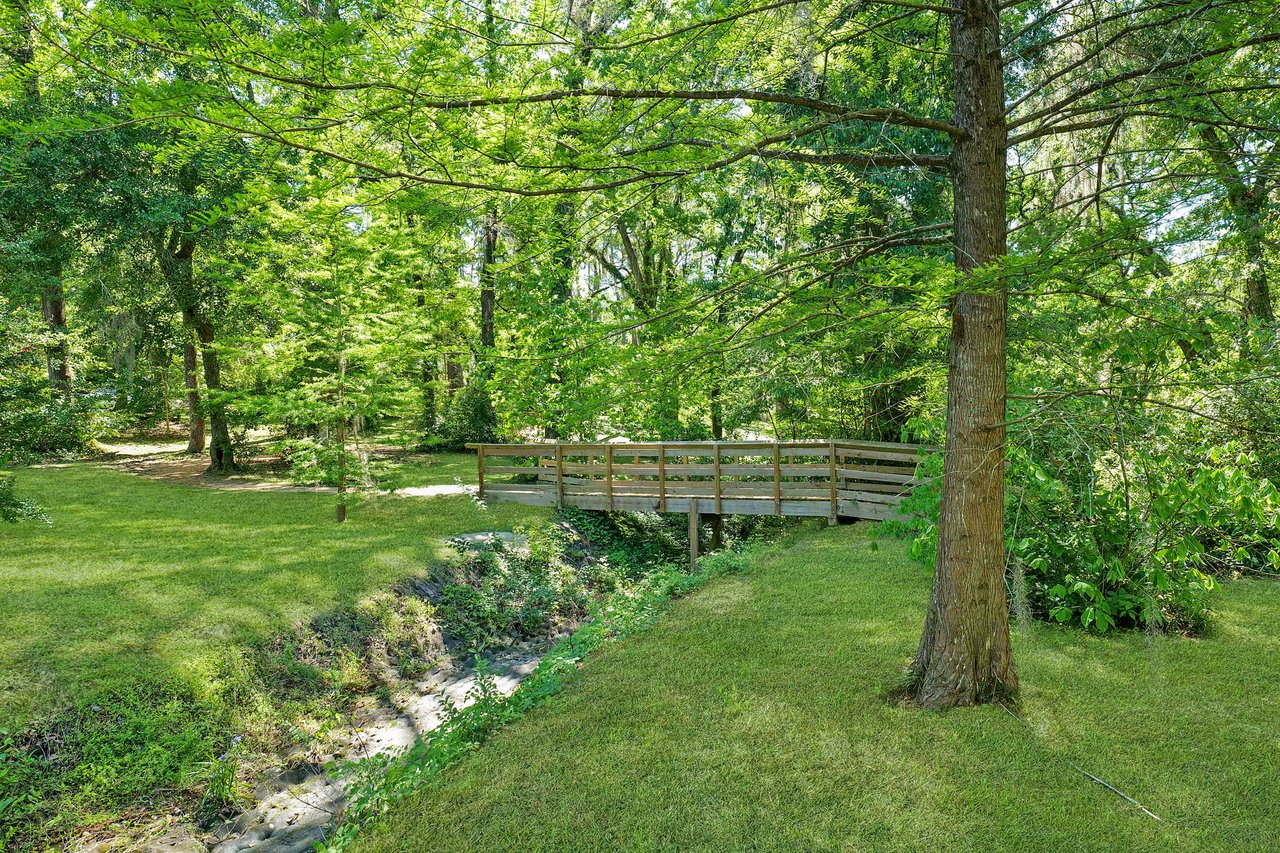 A ground-level view within Lafayette Park, showcasing trees, a pathway, and a small bridge.