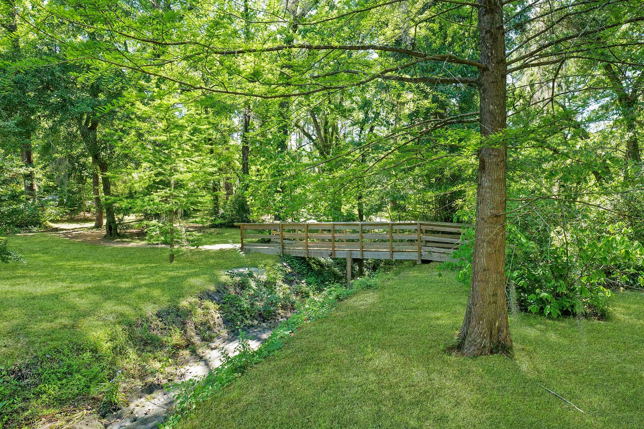 A ground-level view within Lafayette Park, showcasing trees, a pathway, and a small bridge.