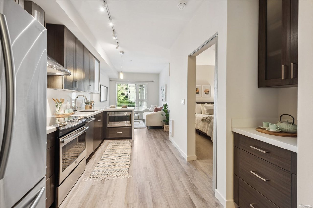 Streamlined condo interior with an open kitchen leading to a cozy living area, bathed in natural light.