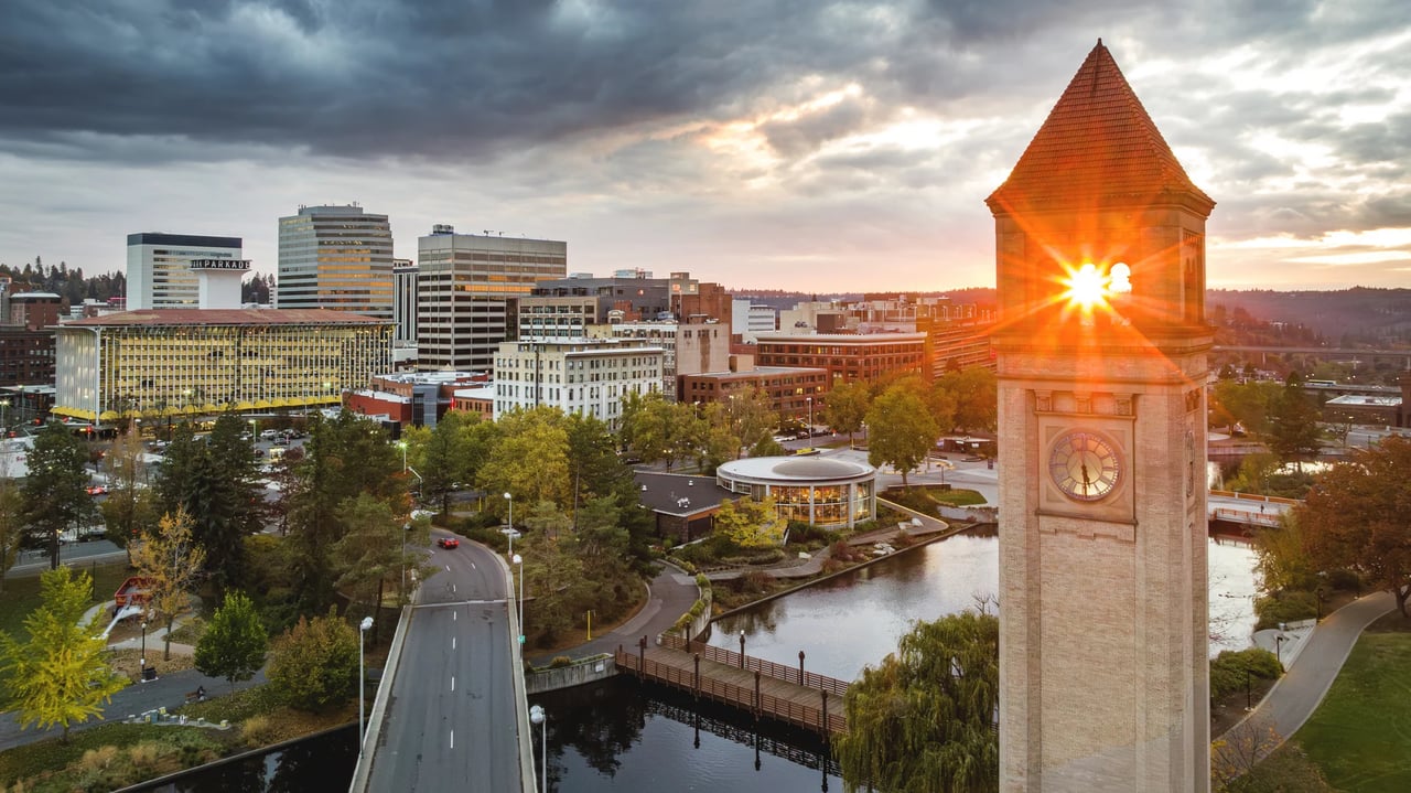 Downtown Spokane at sunset, with the Riverfront Park clock tower overlooking the river and city.