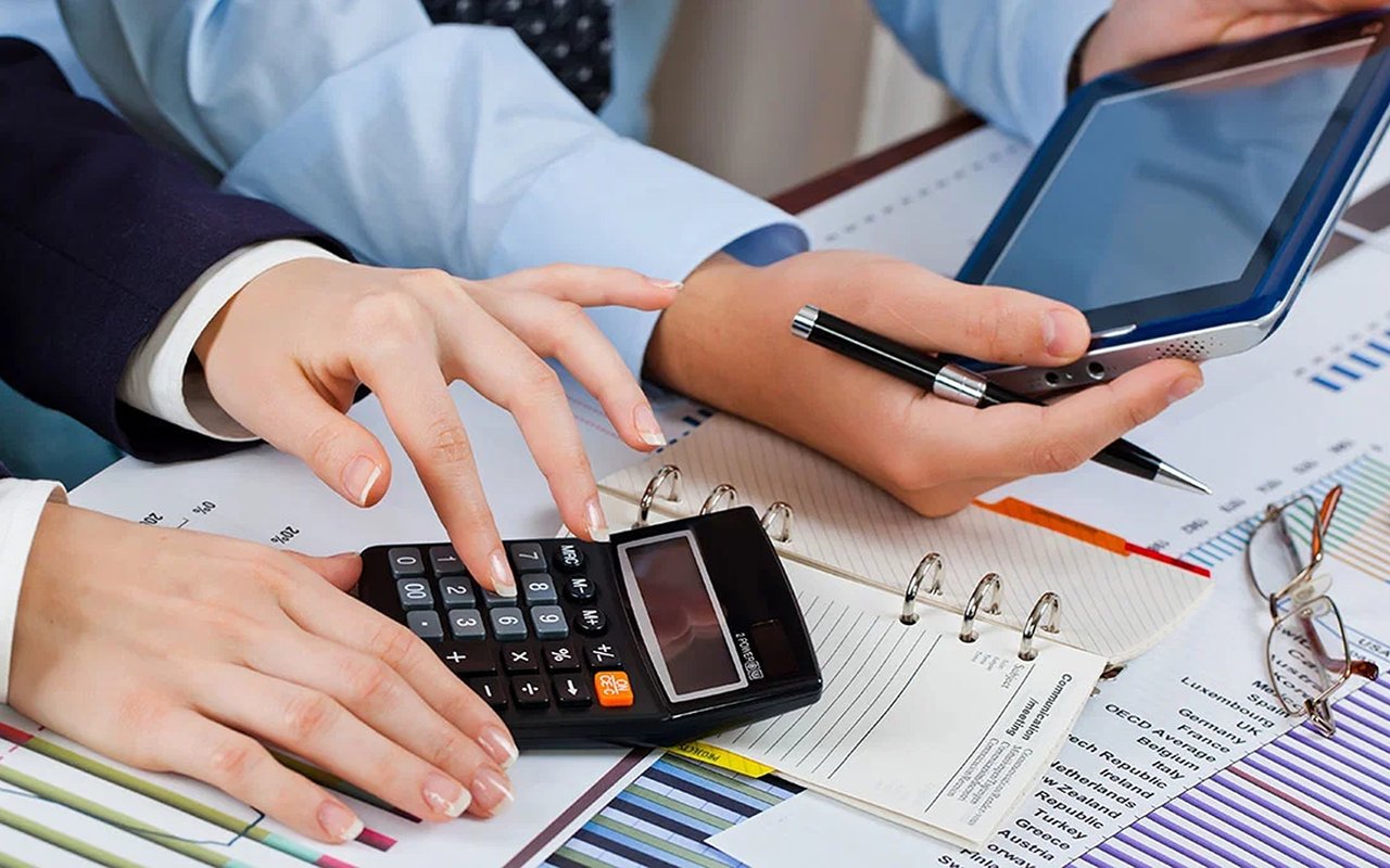 People review financial paperwork with a calculator and tablet.