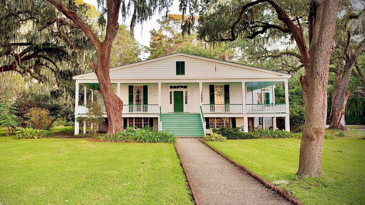 Historic Southern estate at 3 W Bluff Dr on Isle of Hope, GA, featuring a white home with green shutters surrounded by live oaks draped in Spanish moss during golden hour.