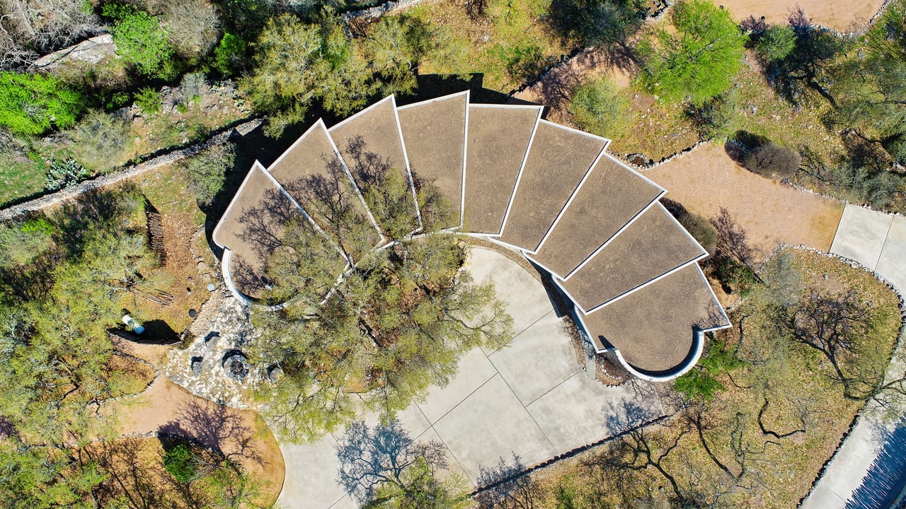 Drone aerial of the fan-shaped roofline and motor court, architect John Covert Watson, builder Don Crowell, Spicewood, Texas.