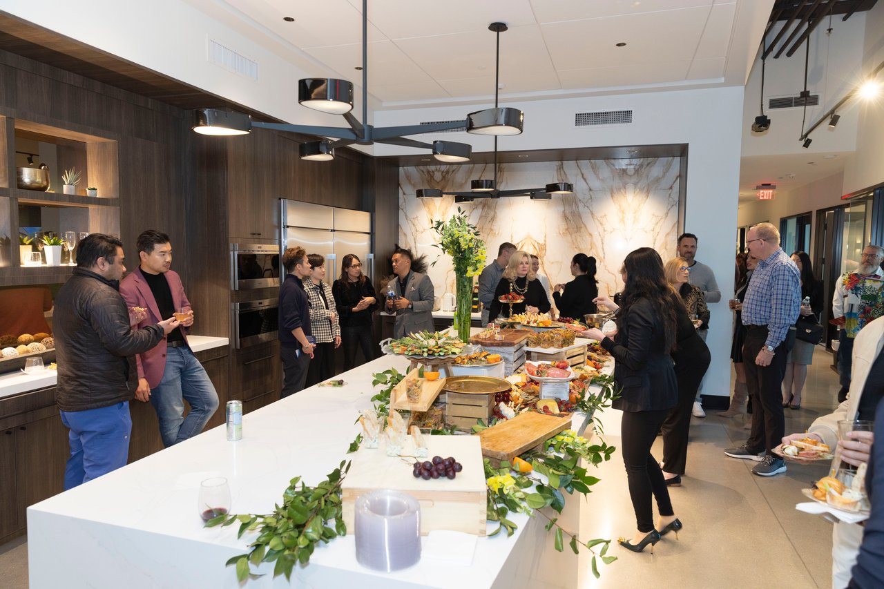 Guests mingle around a buffet in a modern kitchen during an open house.