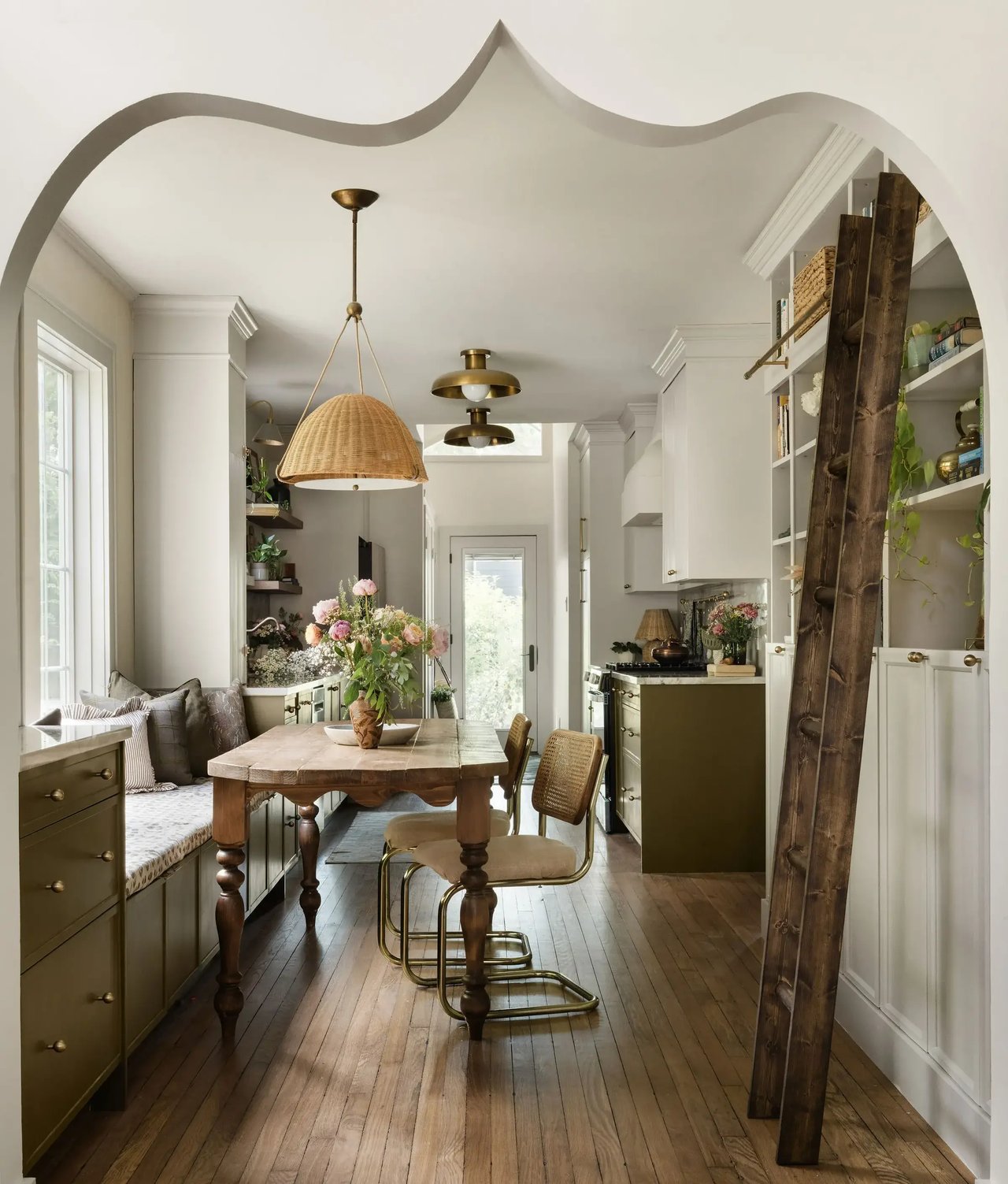 Kitchen dining nook with a built-in bench, brass lighting, and an arched opening.