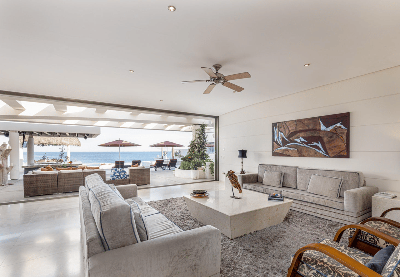 Living room opening onto an oceanfront terrace, with pale sofas and a stone coffee table.