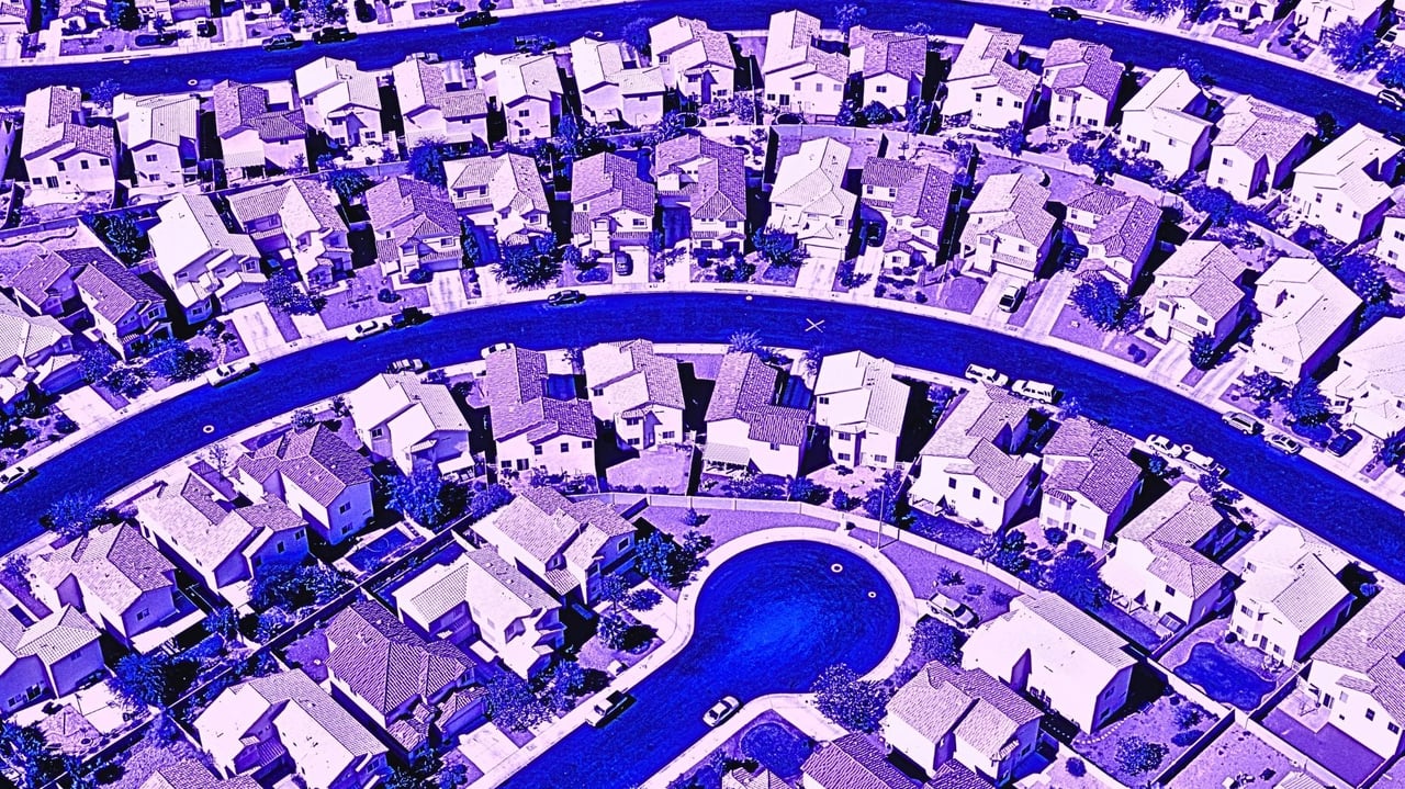 Drone view of a residential subdivision with rows of modern houses along winding streets, edited in vivid purple and blue tones for a high-contrast artistic effect.