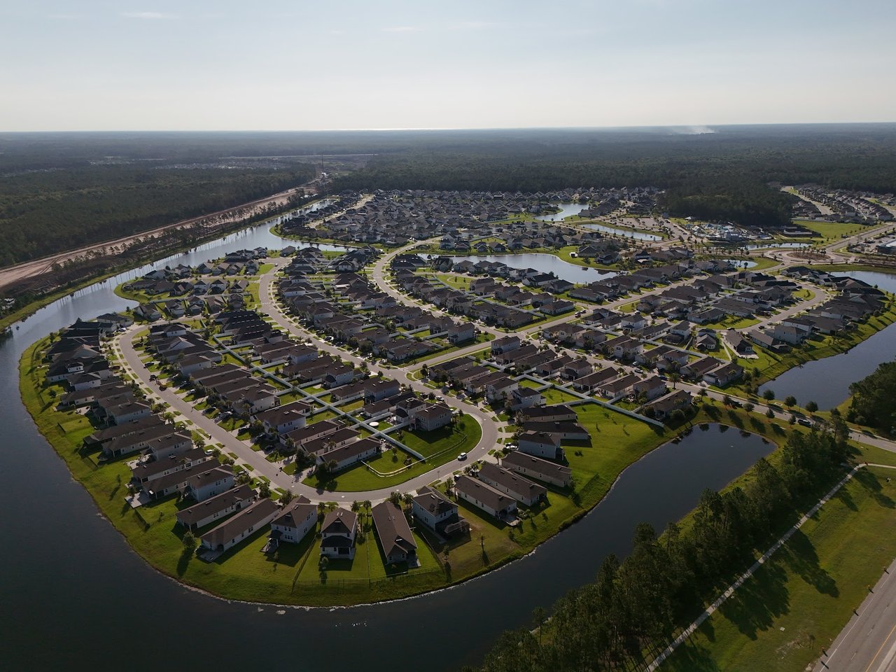 Aerial view of homes arranged along curving streets beside ponds and canals.