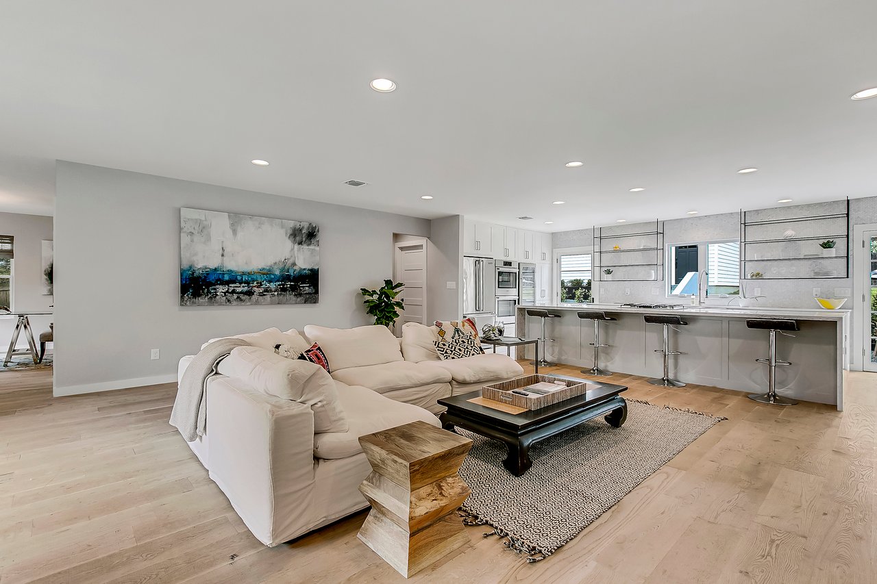 Open-concept living room and kitchen at 1004 Maufrais Street in Clarksville (Old West Austin), Austin, TX, featuring white cabinetry and wide-plank white oak floors throughout.
