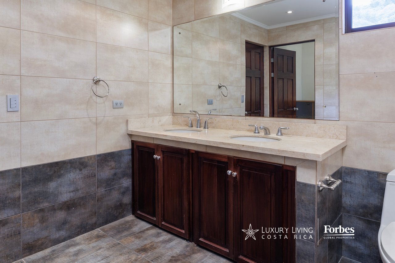 Bathroom with a double-sink vanity, dark wood cabinetry, and beige and charcoal tile.