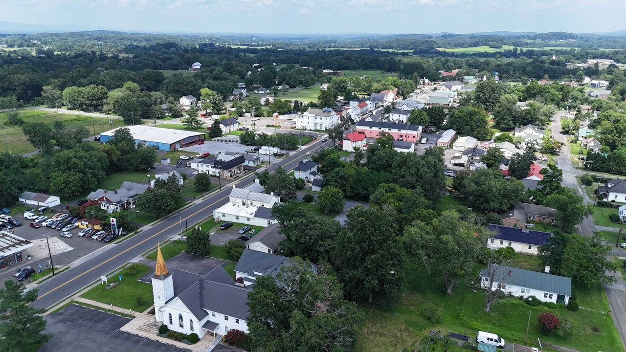 Aerial view of downtown Marshall, Virginia showing Main Street, a white church steeple and rooftops framed by rolling green farmland and hills