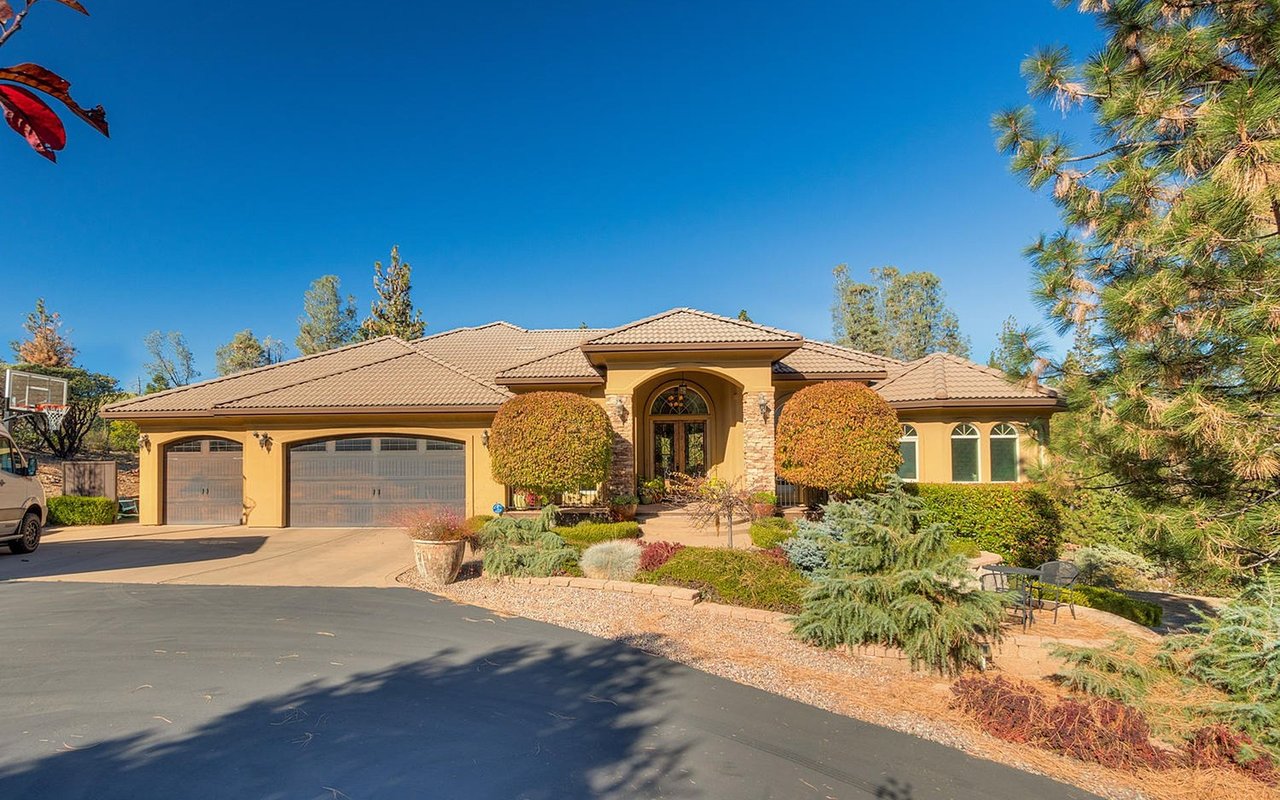 Single-story home with a tan tiled roof, arched entry, and landscaped front yard.