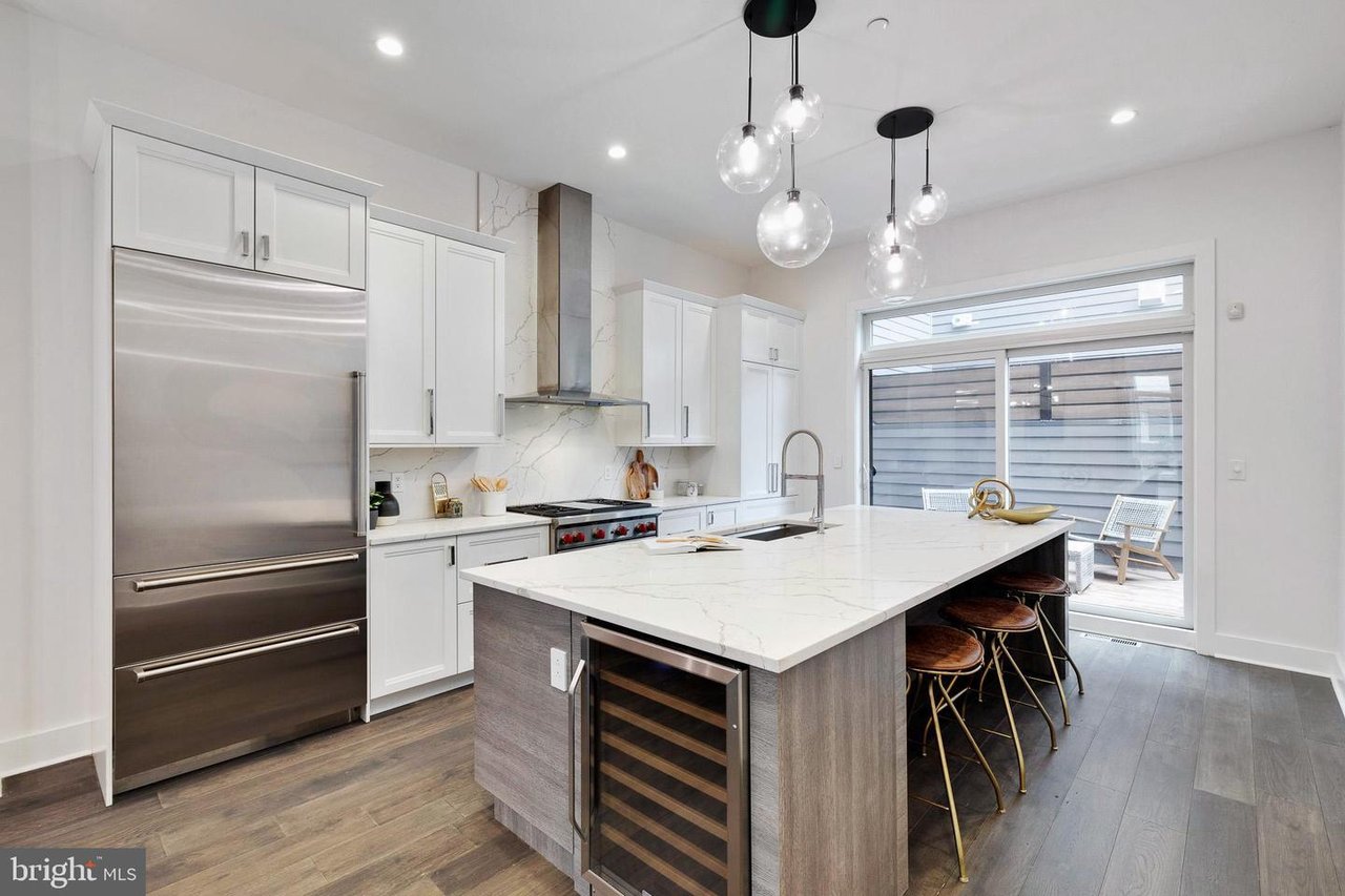 Modern kitchen with a large veined-stone island, stainless steel appliances, and glass doors to a patio.