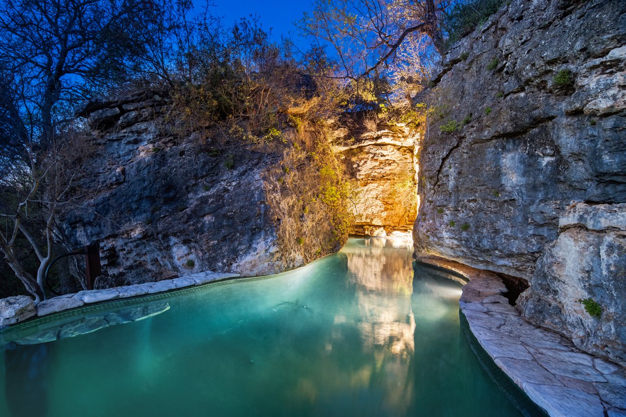 Grotto pool at the base of an uplit limestone cliff and cave at Lick Creek Lodge, Spicewood, Texas.