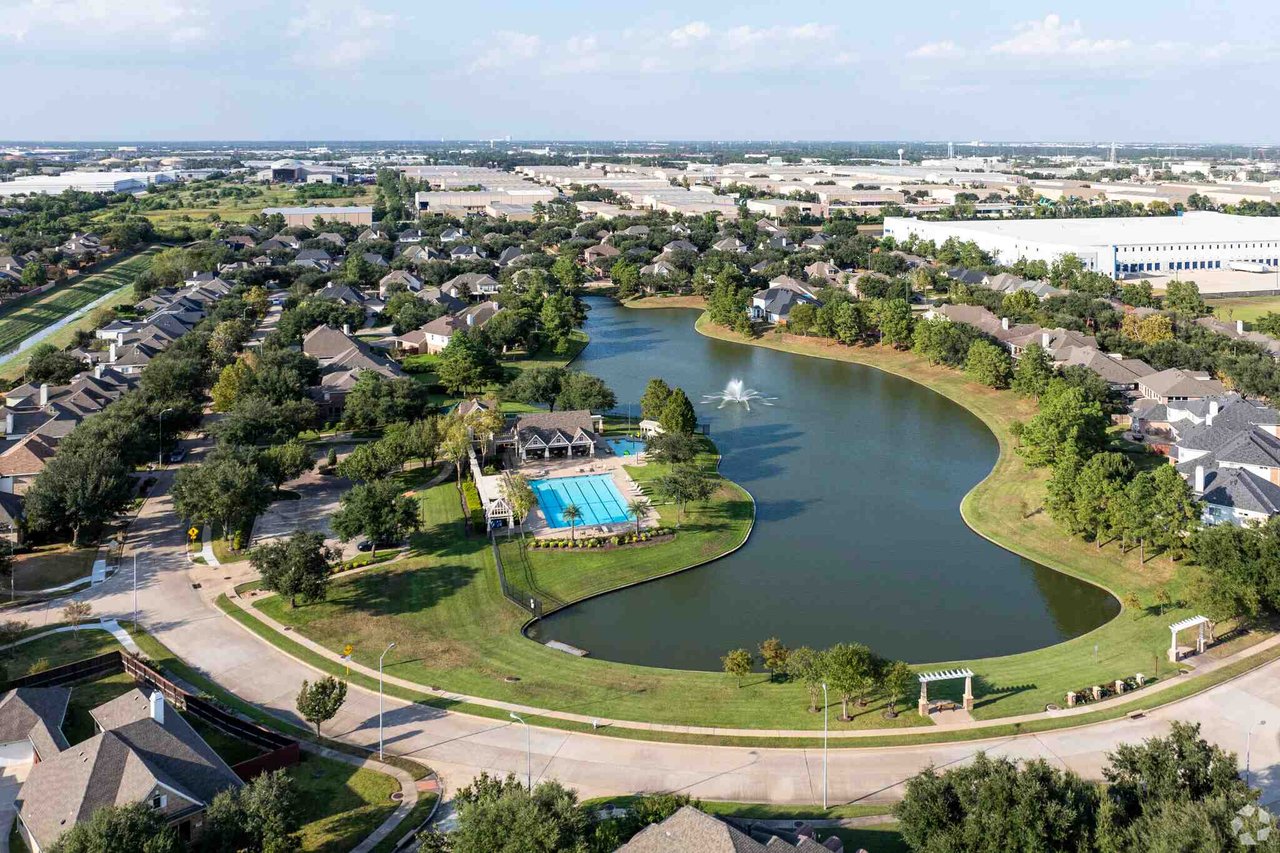 Jersey Village homes surround a lake with a fountain and community pool.