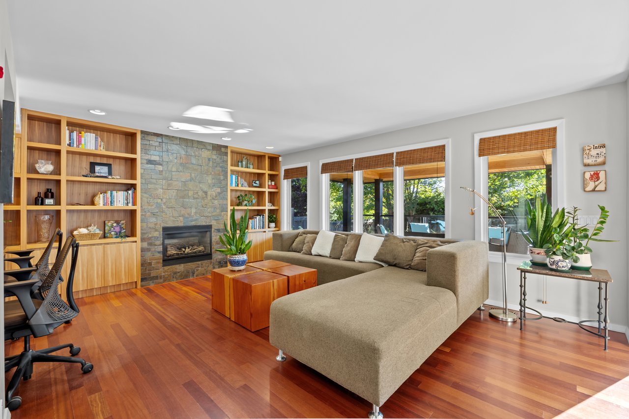 Living room with a beige sectional, hardwood floors, built-in bookshelves, and a stone fireplace.