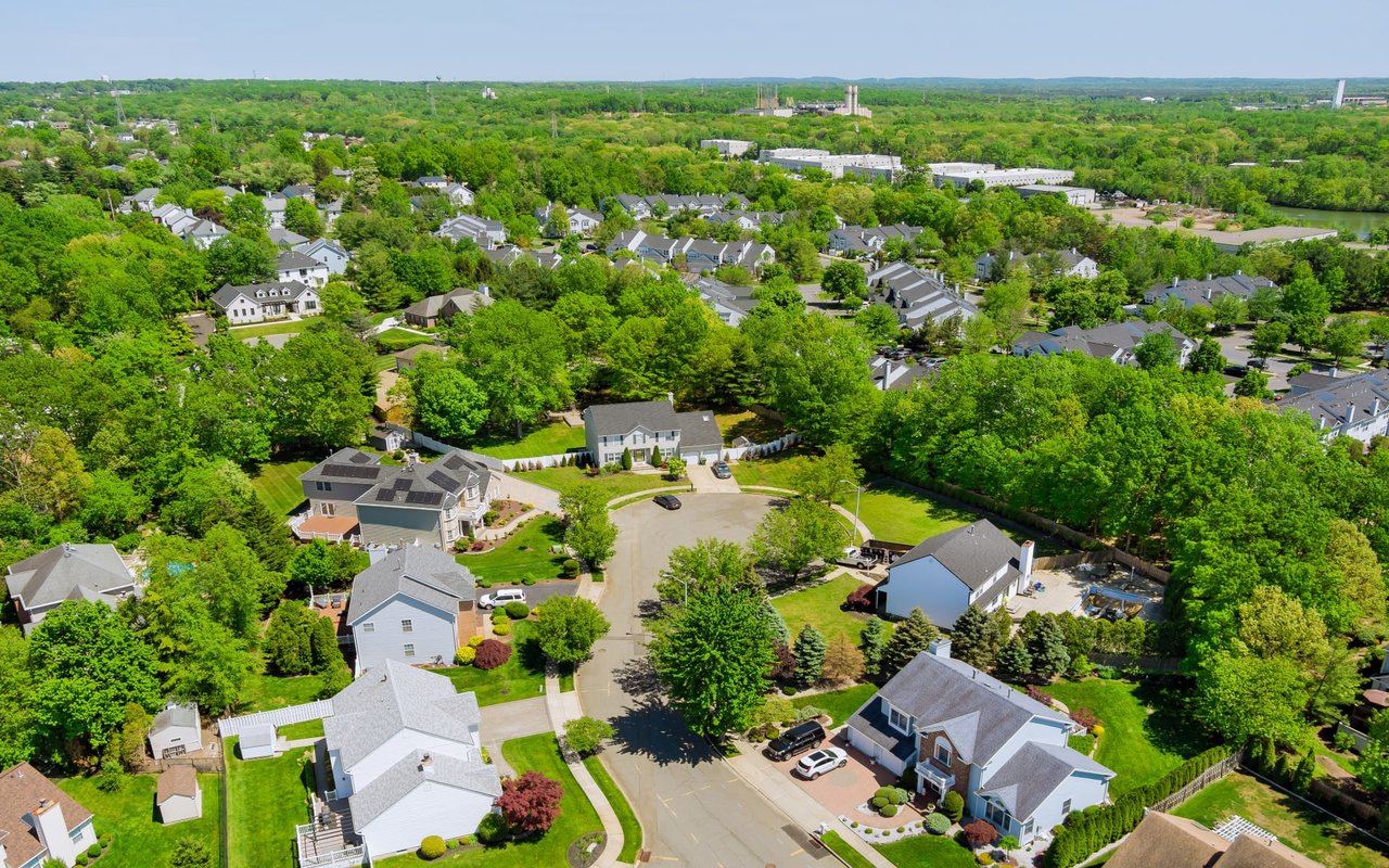 An aerial view of a residential neighborhood with trees scattered throughout the neighborhood and driveways leading to the houses.