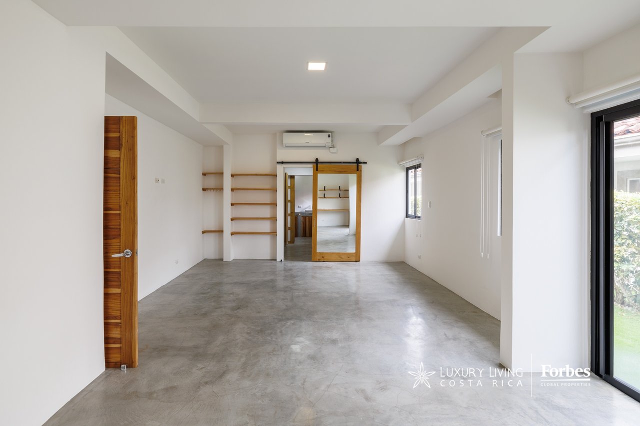 Empty industrial-style room with polished concrete floors, wood shelving, and garden-facing glass doors.