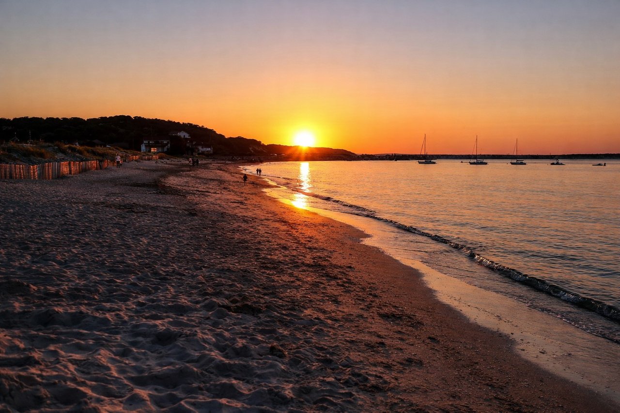 Beach sunset in Hampton Bays with warm golden light over shoreline and coastal sky
