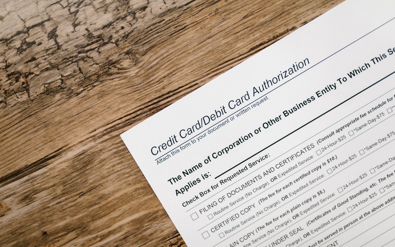 Credit/debit card authorization form lying diagonally on a weathered wooden surface.