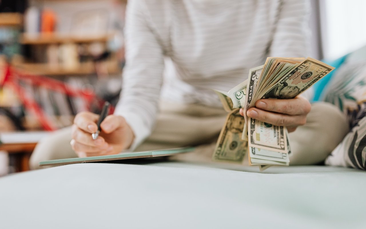 A person counts cash while writing in a notebook.