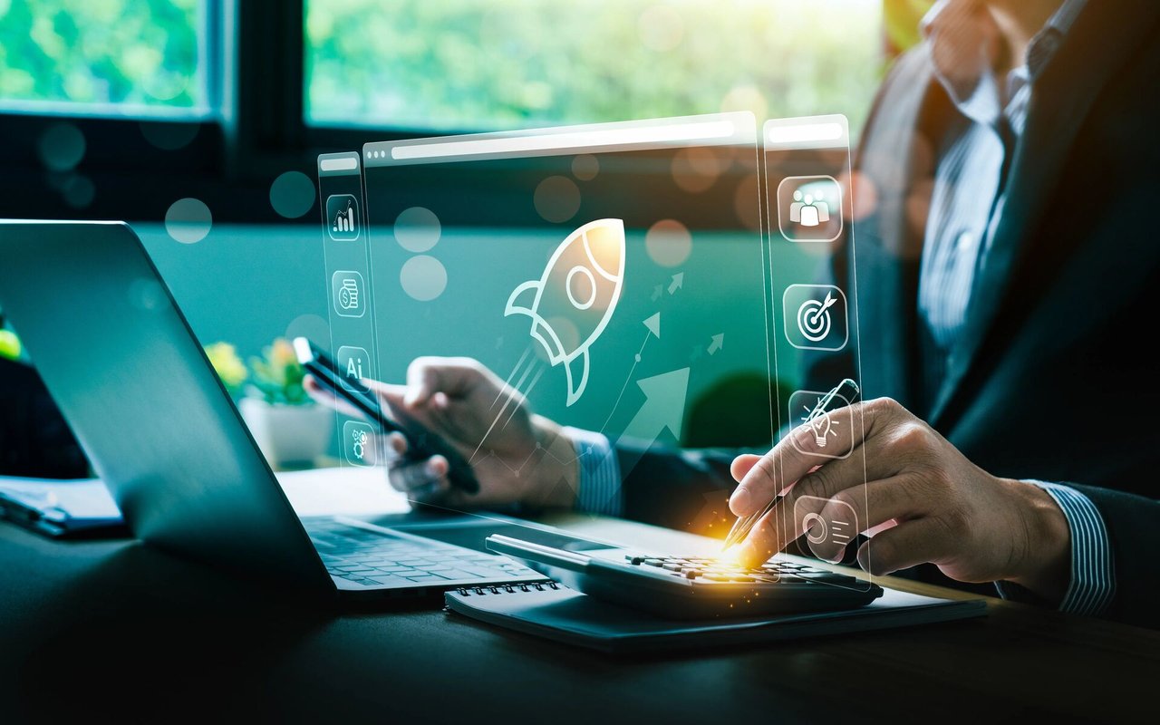 Business professional using a laptop and tablet amid digital growth graphics.