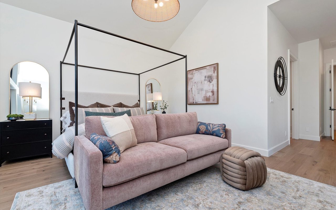 Primary suite featuring a metal four-poster bed and pink velvet couch