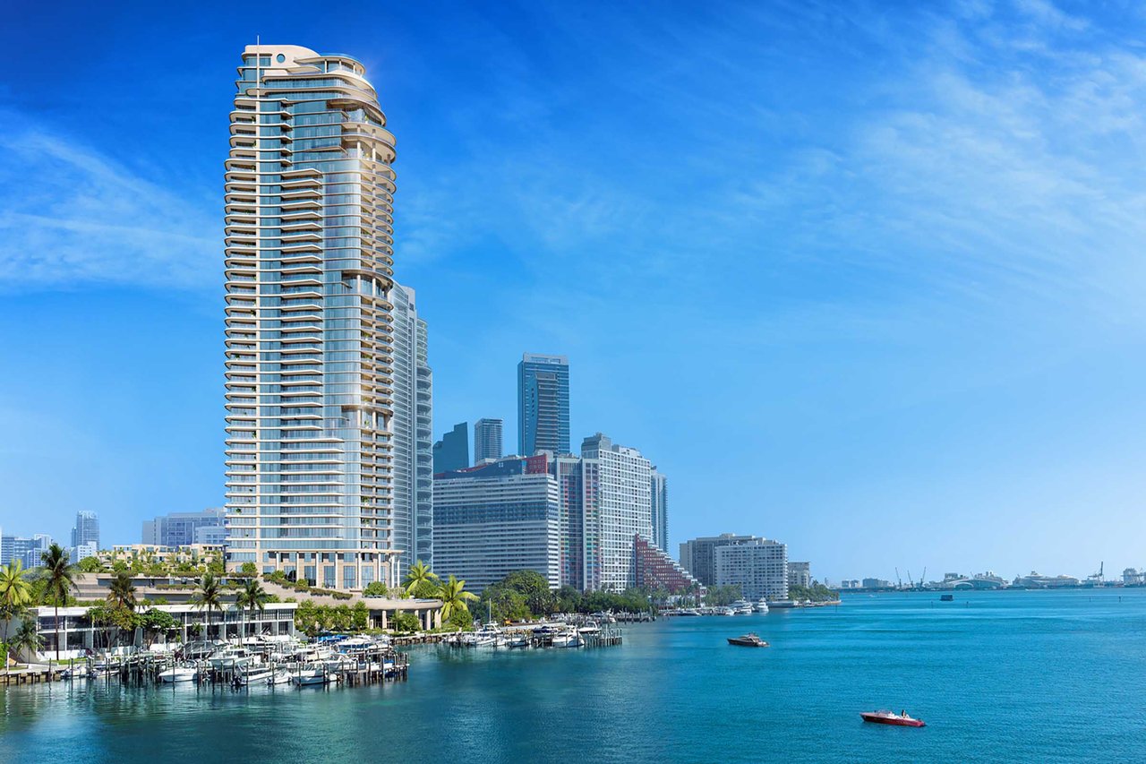 St. Regis Residences tower beside Biscayne Bay, with curved balconies and boats along the waterfront.