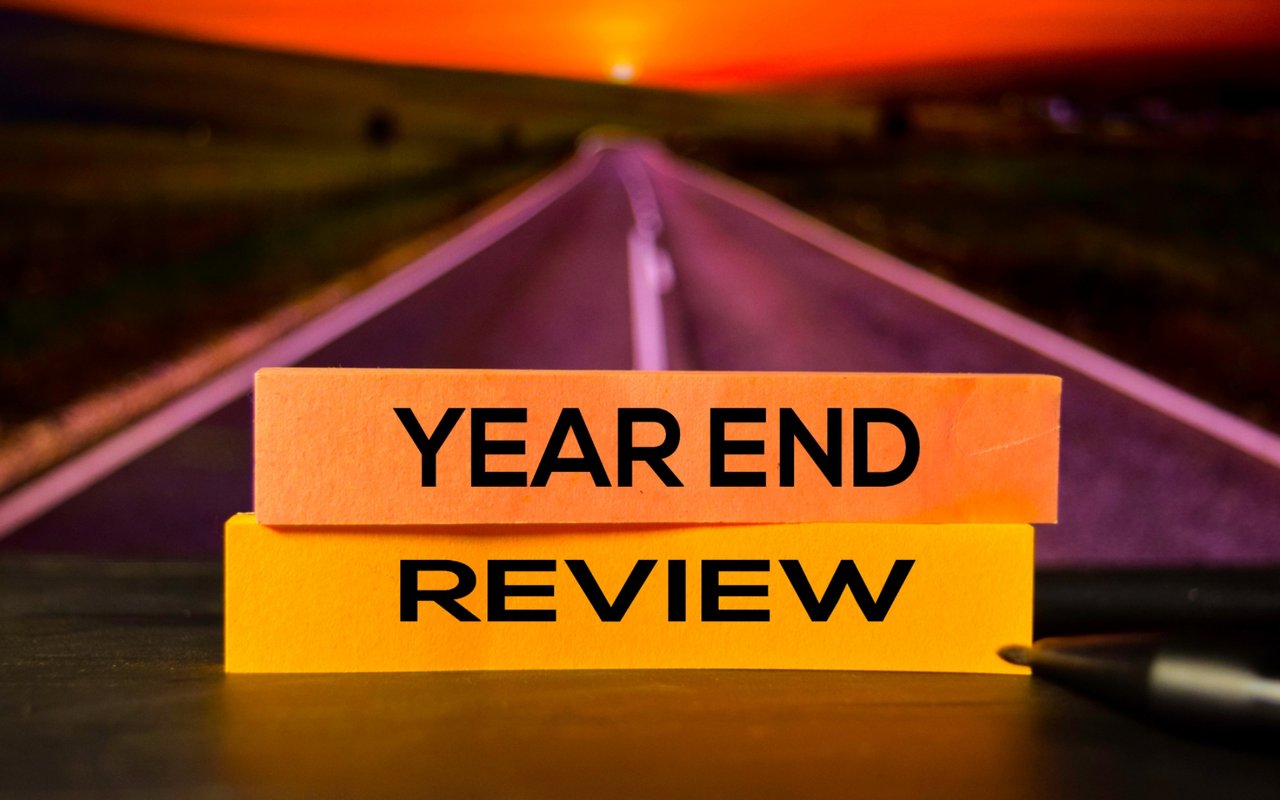 Year-end review written on orange notes against a blurred road at night.