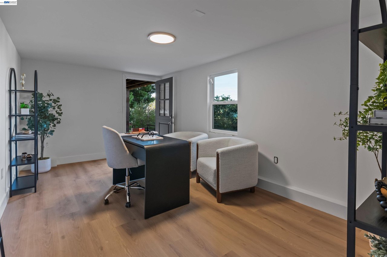 Furnished home office with a black desk and upholstered chairs beside an open door.